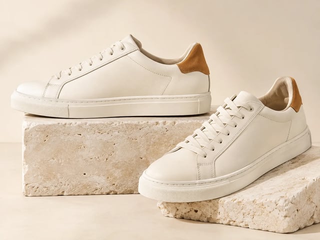 Ivory leather trainers with amber heel tabs on limestone display blocks